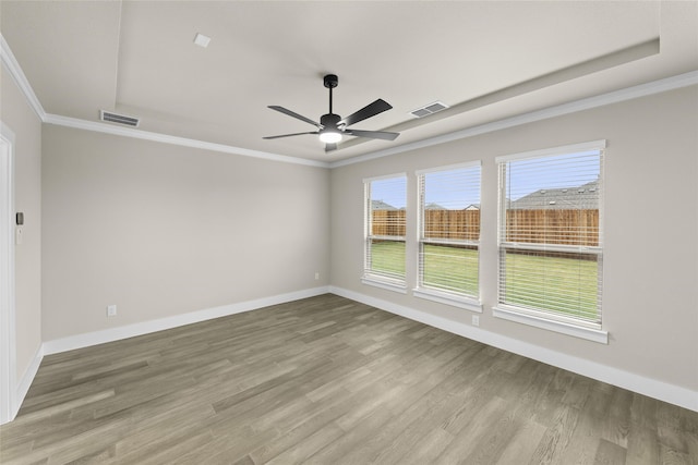 unfurnished room featuring hardwood / wood-style flooring, ceiling fan, crown molding, and a tray ceiling