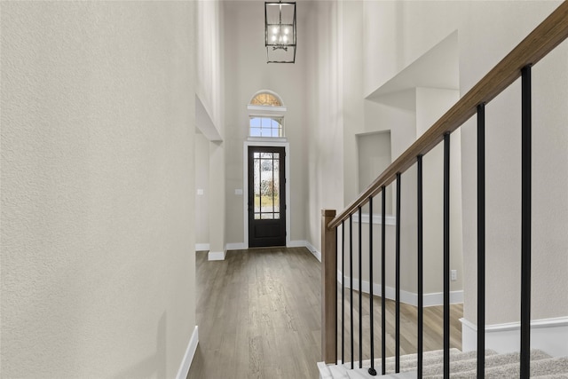 foyer featuring hardwood / wood-style floors, a towering ceiling, and an inviting chandelier