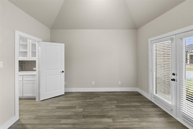 unfurnished bedroom featuring access to exterior, dark hardwood / wood-style floors, and vaulted ceiling