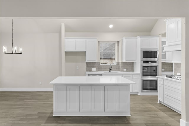 kitchen with sink, white cabinets, stainless steel appliances, and a kitchen island