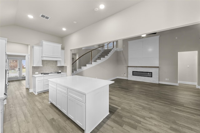 kitchen featuring white cabinets, a kitchen island, lofted ceiling, and light hardwood / wood-style flooring