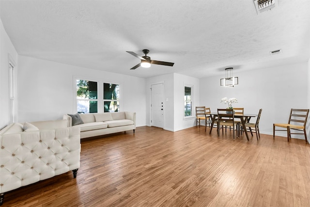 living room with ceiling fan, a textured ceiling, and light hardwood / wood-style flooring