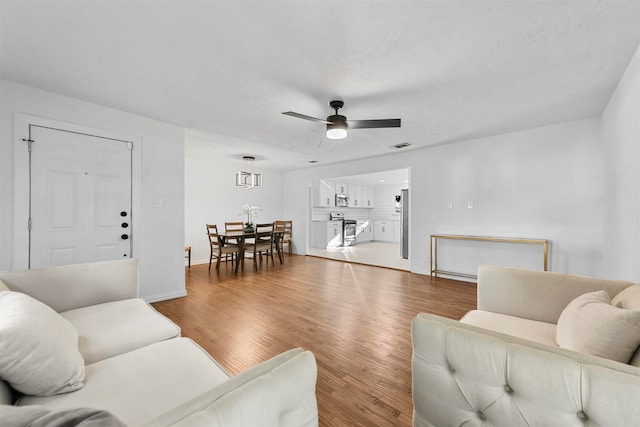 living room with a textured ceiling, hardwood / wood-style flooring, and ceiling fan