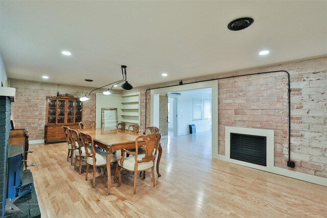 dining room featuring light hardwood / wood-style floors and brick wall