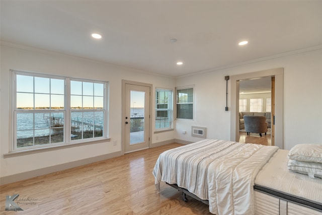 bedroom featuring access to exterior, light wood-type flooring, ornamental molding, and a water view