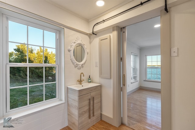 bathroom featuring vanity, a water view, wood-type flooring, and crown molding