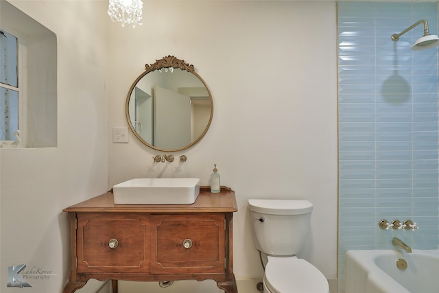 full bathroom featuring a chandelier, vanity, toilet, and tiled shower / bath