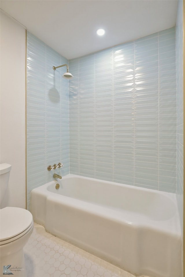 bathroom with toilet and tiled shower / bath