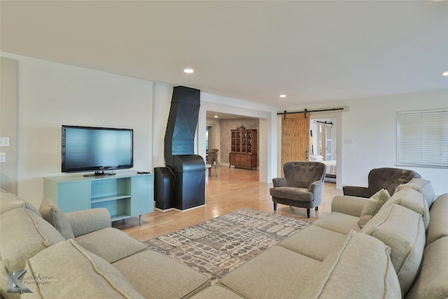 living room with a barn door and light hardwood / wood-style flooring