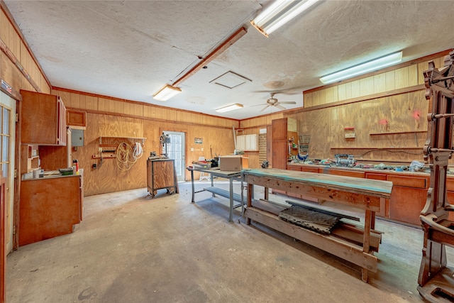 recreation room featuring a workshop area, ceiling fan, and wood walls