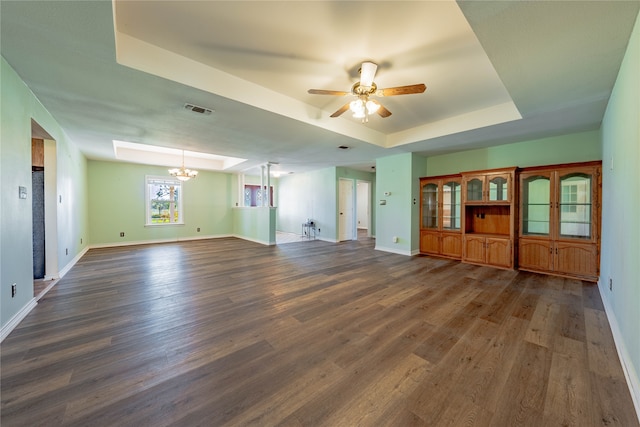 unfurnished living room featuring a tray ceiling, dark hardwood / wood-style flooring, and ceiling fan with notable chandelier