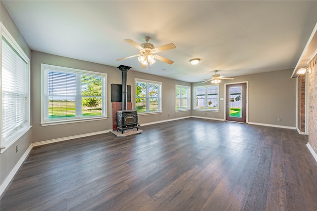 unfurnished living room with a wood stove, ceiling fan, and dark wood-type flooring