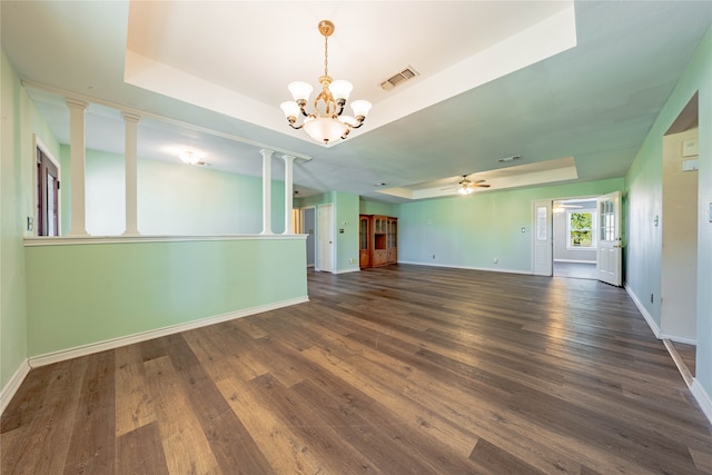 empty room featuring ceiling fan with notable chandelier, dark hardwood / wood-style floors, a raised ceiling, and ornate columns