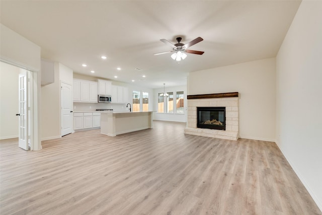 unfurnished living room featuring a ceiling fan, recessed lighting, light wood-style flooring, and baseboards