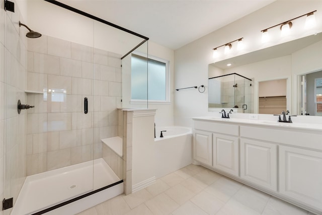 bathroom featuring double vanity, a stall shower, a garden tub, and a sink