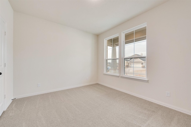 unfurnished room with light colored carpet and baseboards