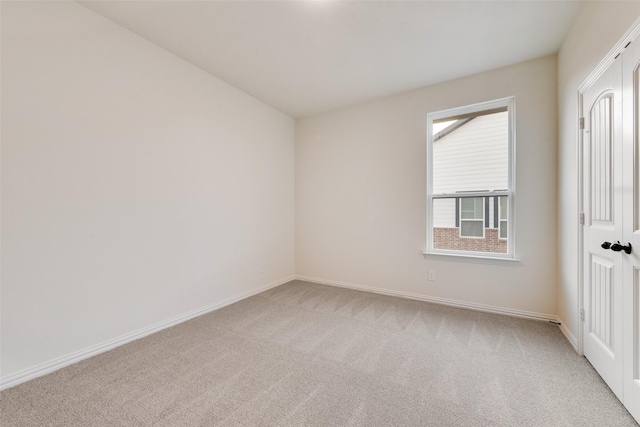 spare room with light carpet and baseboards