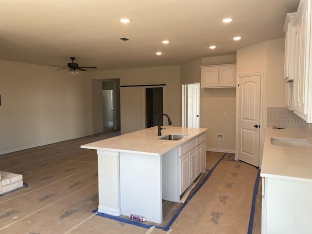 kitchen featuring white cabinets, sink, and an island with sink