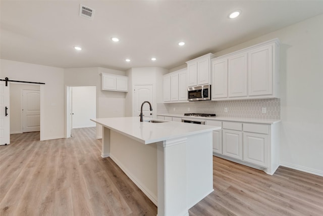 kitchen featuring a barn door, stove, a sink, visible vents, and stainless steel microwave