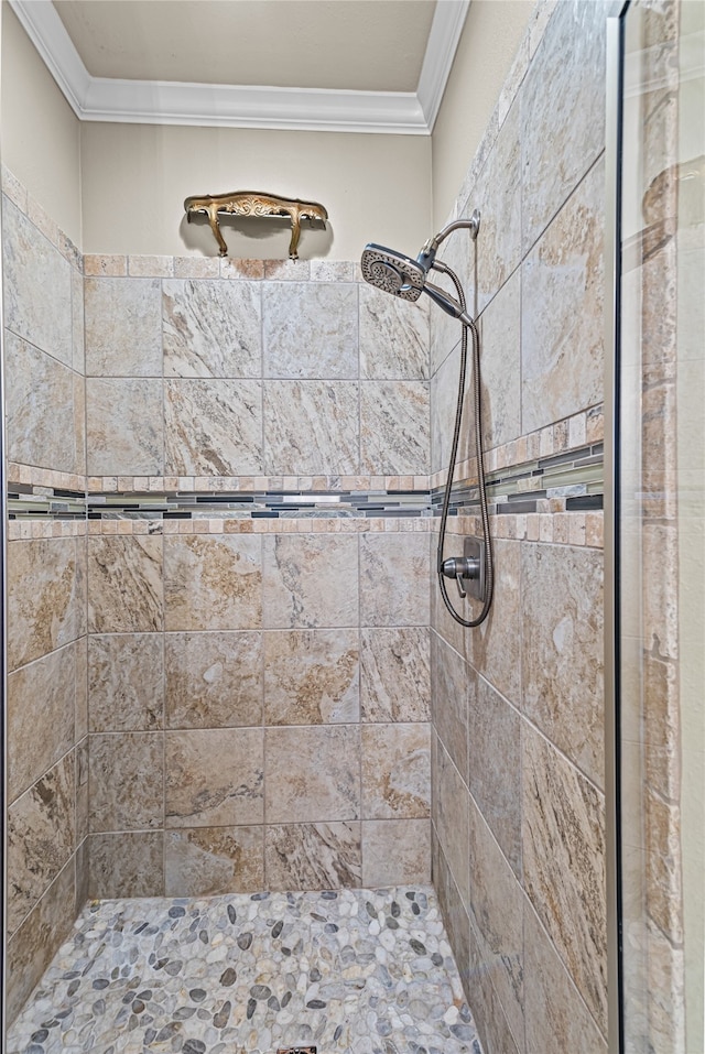 bathroom with a tile shower and ornamental molding