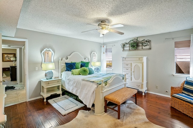 bedroom with ceiling fan, dark hardwood / wood-style flooring, and a textured ceiling