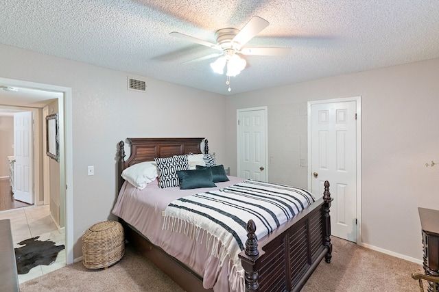 bedroom featuring ceiling fan, light colored carpet, and a textured ceiling