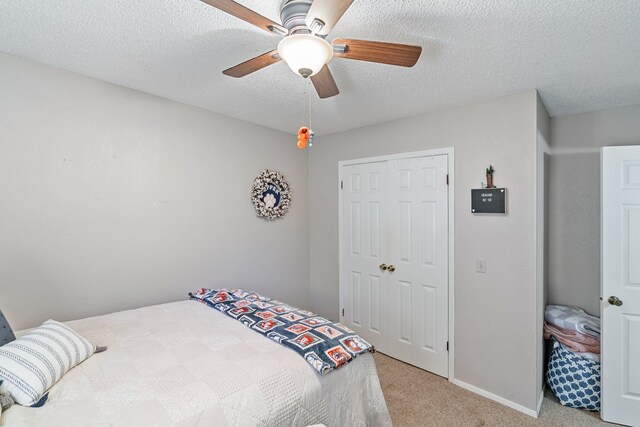 carpeted bedroom with ceiling fan, a closet, and a textured ceiling