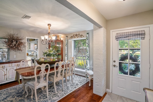 dining area with sink, hardwood / wood-style floors, a textured ceiling, and an inviting chandelier