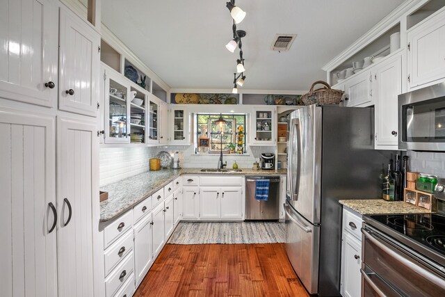 kitchen featuring appliances with stainless steel finishes, light stone counters, sink, hardwood / wood-style flooring, and white cabinets