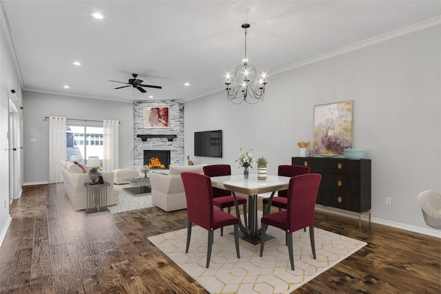 dining space featuring hardwood / wood-style flooring, ceiling fan with notable chandelier, ornamental molding, and a fireplace