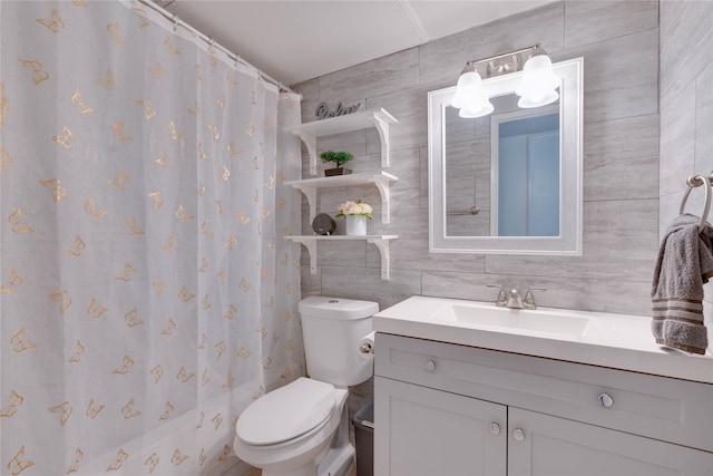 bathroom featuring tasteful backsplash, vanity, tile walls, and toilet