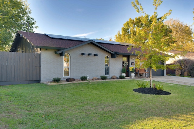 ranch-style house with a garage, a front yard, and solar panels