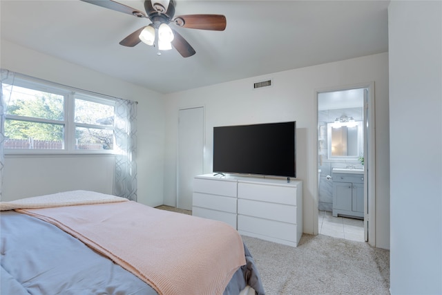 bedroom with light carpet, ensuite bath, and ceiling fan