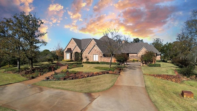 811 Russell Ln, Denison, TX 75021 - french country inspired facade with stone siding, driveway, a lawn, and a chimney