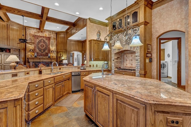 kitchen featuring a large island with sink, washer / clothes dryer, sink, and decorative light fixtures