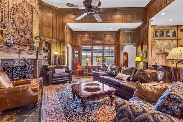 living room with wooden walls, ceiling fan, a high ceiling, and ornamental molding