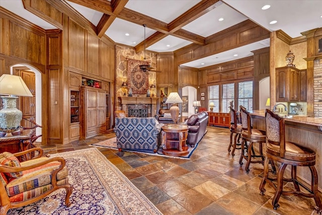 living room with wood walls, a high ceiling, coffered ceiling, beamed ceiling, and a large fireplace