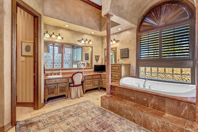 bathroom featuring ornate columns, vanity, and a relaxing tiled tub