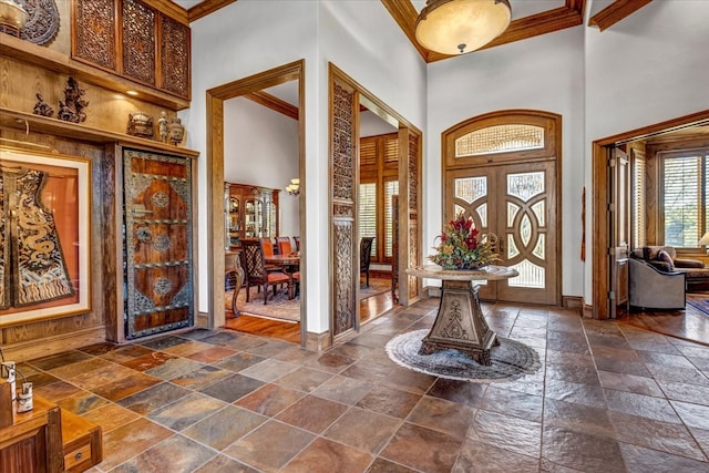 foyer entrance with a towering ceiling and ornamental molding