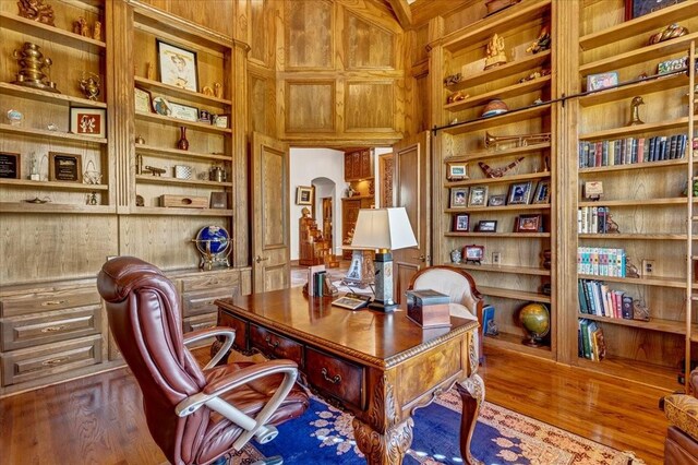 office featuring hardwood / wood-style floors, built in features, and wooden walls