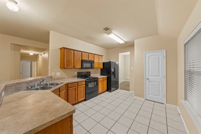 kitchen with sink, light tile patterned flooring, black appliances, and a textured ceiling