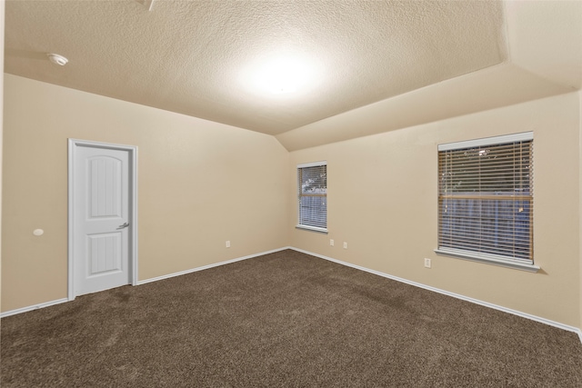 carpeted spare room with a textured ceiling and lofted ceiling