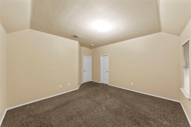 carpeted empty room featuring lofted ceiling and a textured ceiling