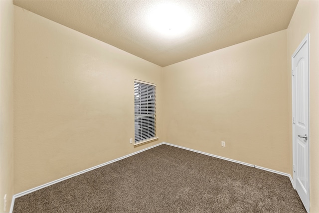 spare room featuring dark colored carpet and a textured ceiling