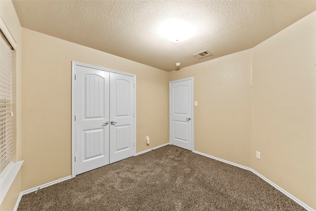 unfurnished bedroom with a closet, carpet floors, and a textured ceiling