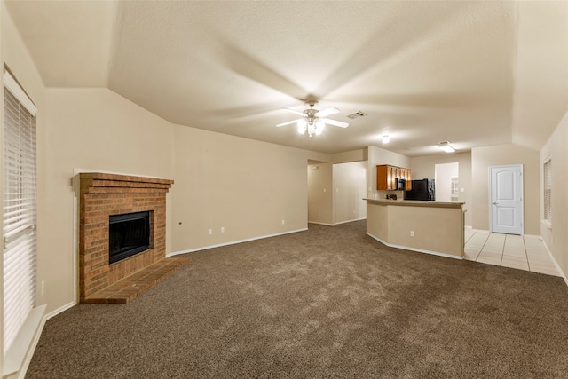 unfurnished living room with ceiling fan, light colored carpet, lofted ceiling, and a brick fireplace