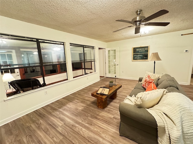 living room with hardwood / wood-style floors, ceiling fan, and a textured ceiling