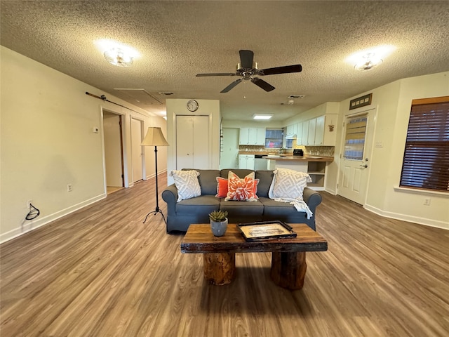 living room with ceiling fan, light hardwood / wood-style floors, and a textured ceiling