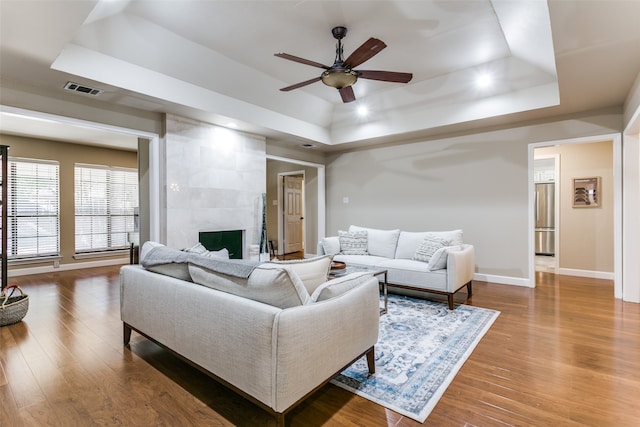 living room featuring a tray ceiling, hardwood / wood-style flooring, and ceiling fan