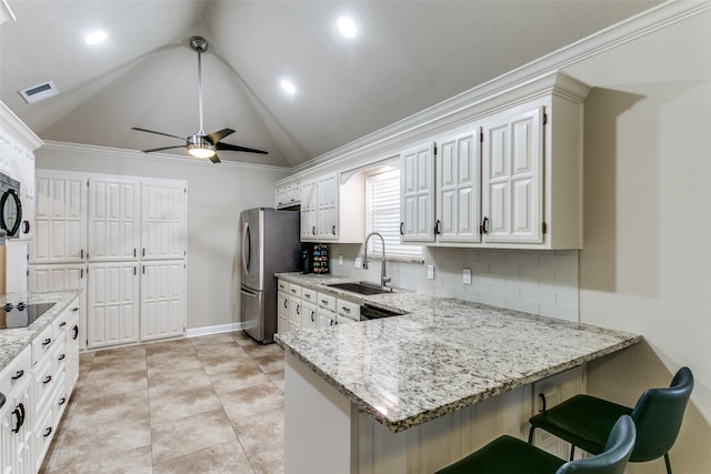 kitchen with kitchen peninsula, white cabinetry, lofted ceiling, and sink